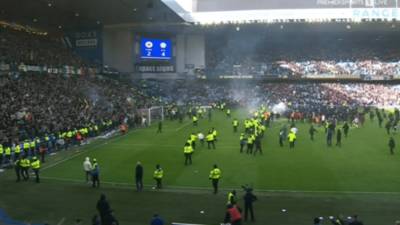 Wild moment hundreds of Rangers and Celtic fans storm onto Ibrox pitch to confront each other and lob FIREWORKS
